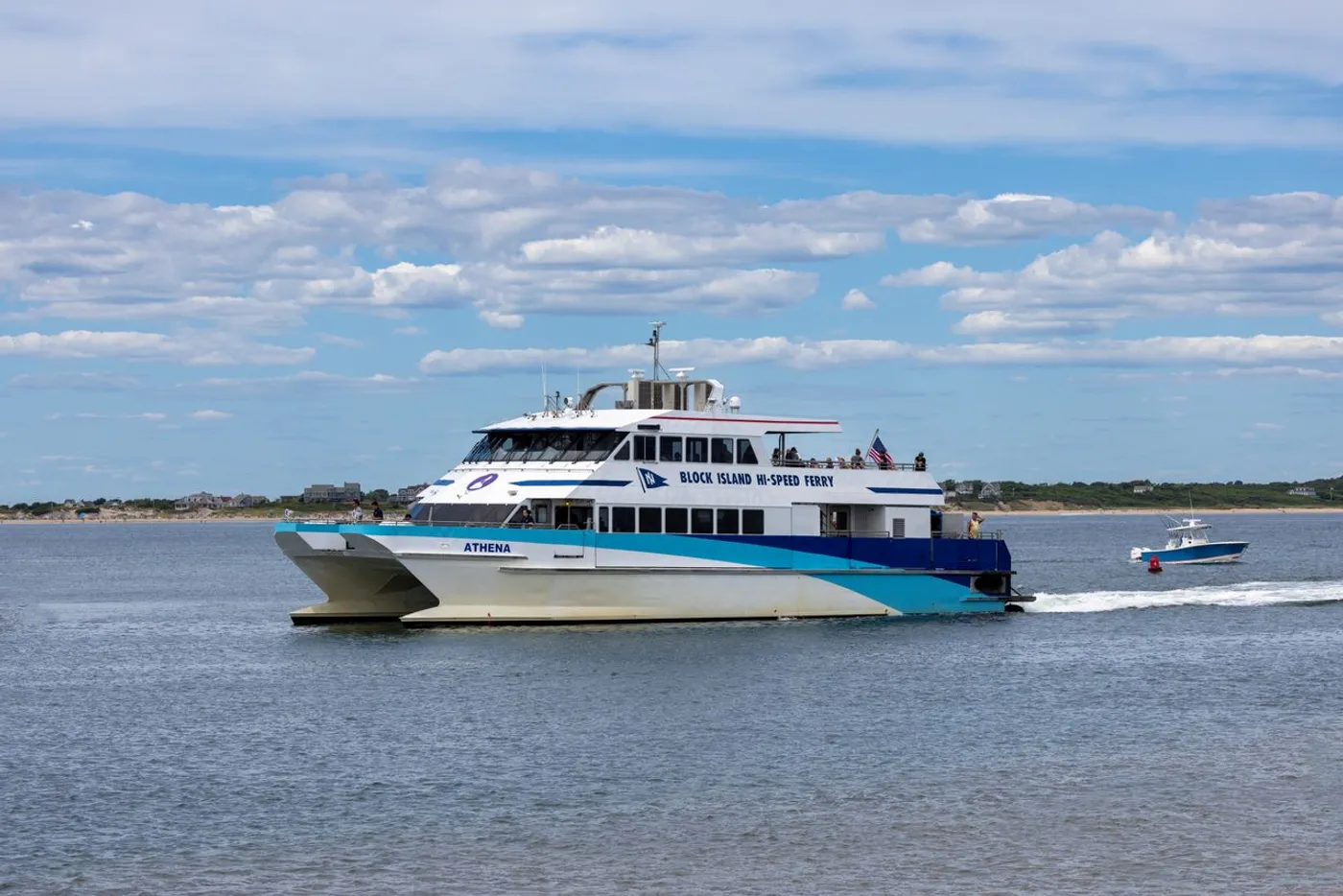 The Block Island Hi-Speed Ferry Athena, a white and blue catamaran, underway on a calm sea under scattered clouds.